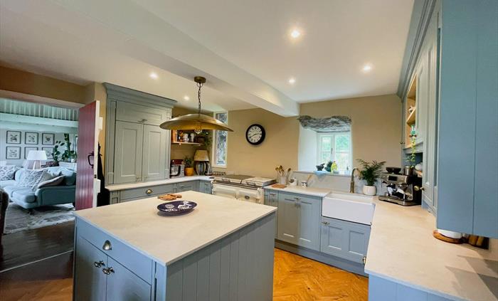 The kitchen at Ysgubor Degwm self catering holiday let near Pwllheli in North Wales. Pale blue units with cement style work tops and brass light.
